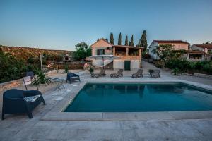 a swimming pool with chairs and a house at Holiday house DM in Bobovišća