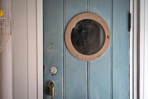 a blue door with a round window on it at Finest Retreats - The Watchtower at Western Watch in Lower Boscaswell