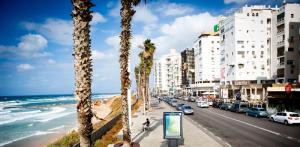a city street with palm trees and the ocean at חופים מול הים in Bat Yam