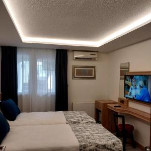 Habitación de hotel con cama, escritorio y TV. en Dab Hotel Ulus, en Ankara