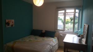 1 dormitorio con cama, escritorio y ventana en maison chaleureuse avec jardin, en Libourne