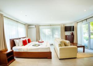 a large bedroom with a bed and a chair at Searenity Beach Villa in Diani Beach