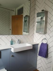 ein Badezimmer mit einem Waschbecken, einem Spiegel und einem lila Handtuch in der Unterkunft Heart of Stoke Newington in London