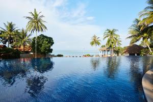 a swimming pool with palm trees and the ocean at Rawi Warin Resort And Spa - SHA Extra Plus in Ko Lanta