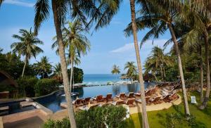 a resort with a pool and chairs and the ocean at Rawi Warin Resort And Spa - SHA Extra Plus in Ko Lanta