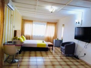 Habitación de hotel con cama, mesa y TV en ZUNOX GUEST HOUSE en Freetown