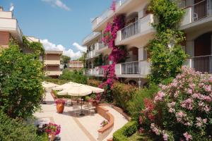 un edificio de apartamentos con un patio con sombrilla y flores en I Cinque Pini en Follonica