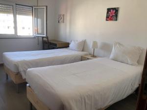 a hotel room with two beds with white sheets at Santiago Guesthouse in Aveiro