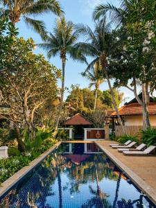 a resort swimming pool with lounge chairs and palm trees at Rawi Warin Resort And Spa - SHA Extra Plus in Ko Lanta