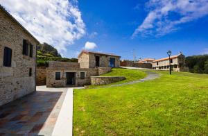 a stone house with a grassy yard next to a building at Sal de Mar Apartamentos in Muxia