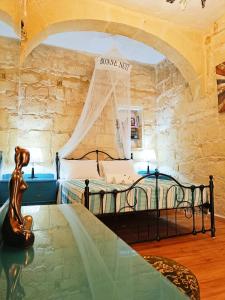 ein Schlafzimmer mit einem Bett in einem Zimmer mit Steinwänden in der Unterkunft Fusion Homestay Accommodation in Mosta