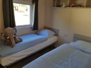 un osito de peluche sentado en una cama en un dormitorio en Chalet Silbermöwe am Kransburger See 548 en Kransburg