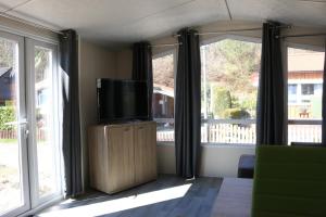 a living room with a tv and two windows at Chalet Silbermöwe am Kransburger See 548 in Kransburg