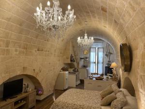 a bedroom with a stone wall with a bed and a chandelier at Casa Rebecca 14 in Monopoli