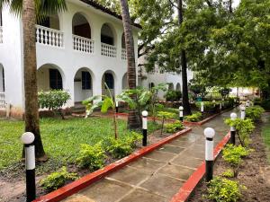 a path in front of a building with trees and plants at Maasai Resort in Mombasa