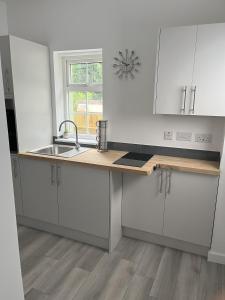 uma cozinha com armários brancos, um lavatório e uma janela em 2BR Bungalow, Garden, Near Races em Newmarket