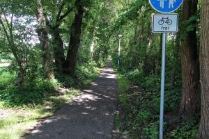 a bike trail with a sign on the side of it at Ferienhaus am Ostfrieslandwanderweg, 15177 in Leer