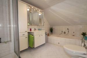 a bathroom with a toilet and a tub and a sink at Ferienhaus am Ostfrieslandwanderweg, 15177 in Leer +24 photos