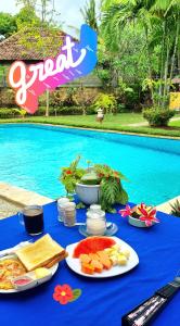 une table bleue avec de la nourriture à côté d'une piscine dans l'établissement Balinda Rooms & Villa, à Lovina