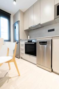 eine Küche mit Küchengeräten aus Edelstahl und einem Stuhl in der Unterkunft Apartamento Capri Living Suites en Castellon in Castellón de la Plana