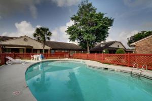 uma grande piscina num quintal com uma cerca vermelha em HOTEL DEL SOL - Pensacola em Pensacola