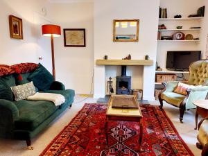 a living room with a green couch and a fireplace at Branklyn Garden Cottage in Perth