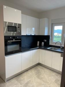 a kitchen with white cabinets and a microwave at Apartman Jurišić in Posušje