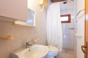 a white bathroom with a sink and a toilet at Villa Nzina in Castellammare del Golfo