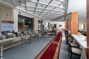a dining room with tables and chairs and a cafeteria at Tanger Med Hotel, Conference & Catering in Ghdar Defla