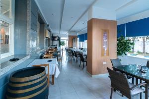 Un restaurante con mesas y sillas y una sala con paredes azules. en Tanger Med Hotel, Conference & Catering, en Ghdar Defla