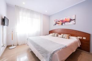 a bedroom with a large bed with a wooden headboard at Aparthotel Napols - Abapart in Barcelona