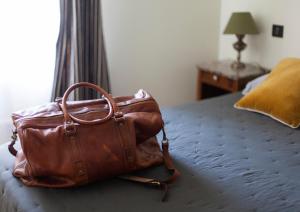 a brown bag sitting on top of a bed at Auberge des braconniers in Ampus