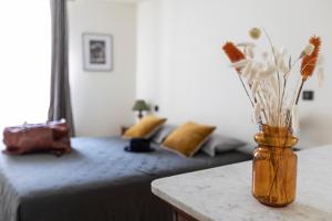 a vase with flowers on a table next to a bed at Auberge des braconniers in Ampus