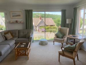 a living room with a couch and chairs and a large window at Coldstream Cottage in Dale