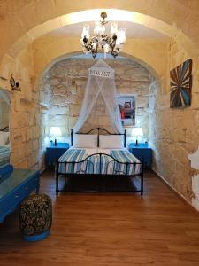 a bedroom with a bed in a stone wall at Fusion Homestay Accommodation in Mosta