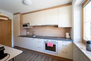 une cuisine avec des armoires blanches et une cuisinière dans l'établissement Ferienhaus Christine Bauer, à Hintergöriach