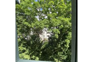 una ventana con vistas a una casa a través de los árboles en Private Apartment, en Hannover