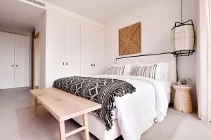 a white bedroom with a bed and a wooden table at Verdelago Resort in Praia Verde
