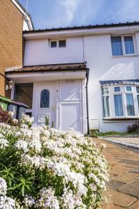 a white house with a white door and some flowers at Spacious White House 3 bedrooms with parking, garden, Wi-Fi in Telford