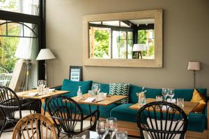 Un restaurante con un sofá azul y mesas y sillas. en Domaine de Bellevue - Restaurant & Spa, en Neufmoutiers-en-Brie