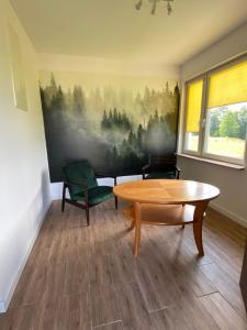 ウストロンにあるPokoje Green Houseのテーブルと椅子、壁画が備わるお部屋