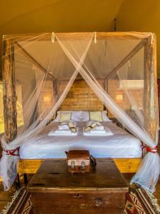 a bedroom with a canopy bed with a wooden table at TERRA - Saturnia tented lodges in Saturnia