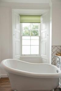 uma banheira branca na casa de banho com uma janela em Hexham House Penthouse Apartment Seven em Hexham