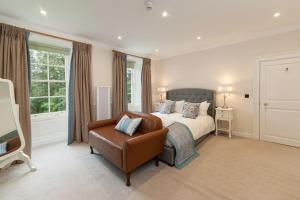 a bedroom with a bed and a leather chair at Hexham House Penthouse Apartment Seven in Hexham