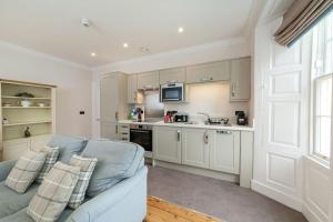 a living room with a blue couch and a kitchen at Hexham House Penthouse Apartment Seven in Hexham