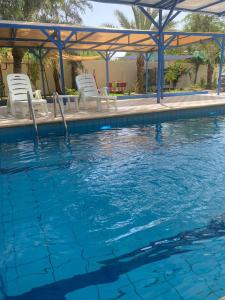 a swimming pool with chairs and a gazebo at villa Rima in Shūnat Nimrīn