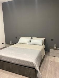 een slaapkamer met een bed met witte lakens en kussens bij Holiday House Fifteen in Catania