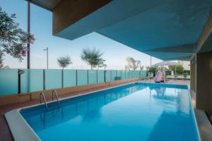 een zwembad met blauw water in een gebouw bij Hotel Crown in Rimini