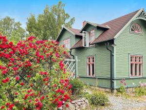 a green house with red flowers in front of it at Holiday home RONNEBY X in Ronneby
