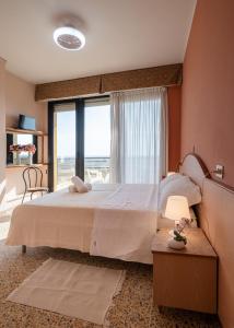 a bedroom with a large bed and a large window at Hotel Crown in Rimini